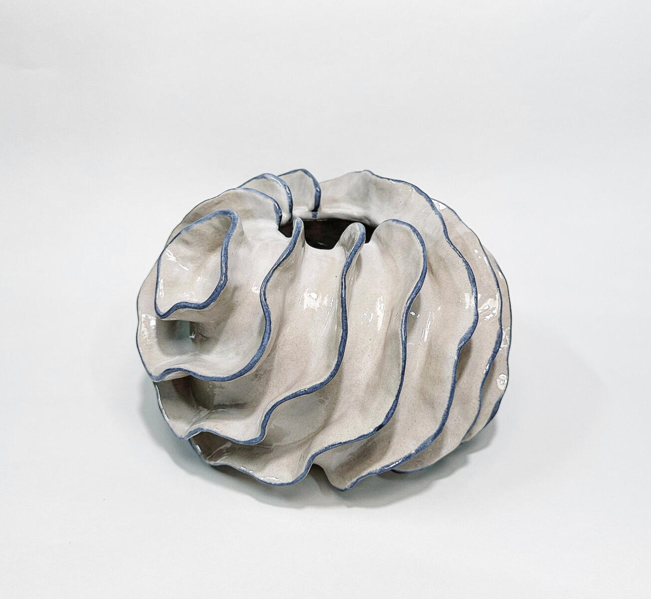 Sea-inspired sculptural ceramic vase — organic elegance from Natty Ceramics atelier in Utrecht Handcrafted white ceramic vase with layered blue folds, resembling sea waves and organic marine forms